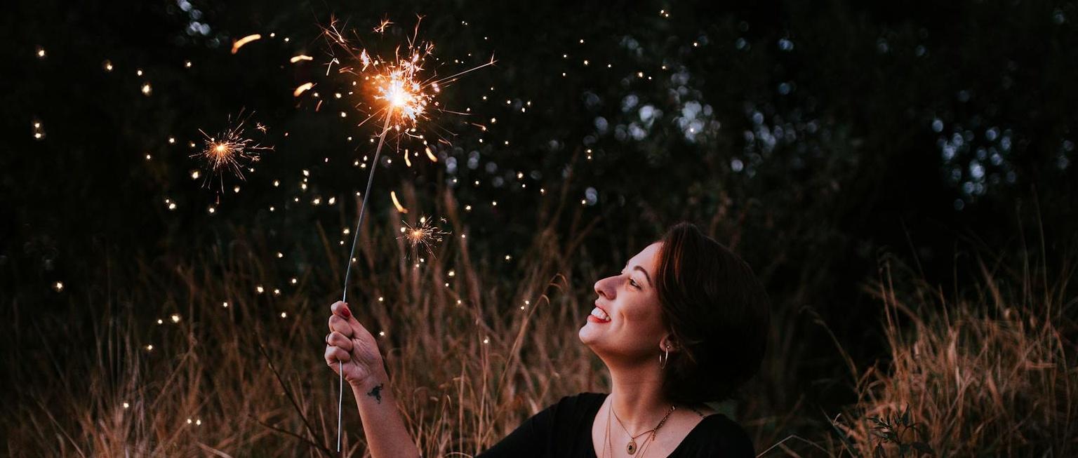 Mujer sosteniendo una bengala bajo el cielo nocturno