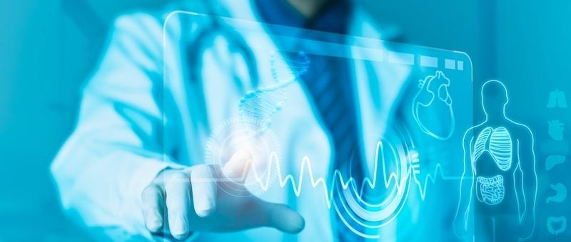 Profesional médico con bata blanca tocando interfaz digital que muestra el ritmo cardíaco y la anatomía humana en tonos azules.
