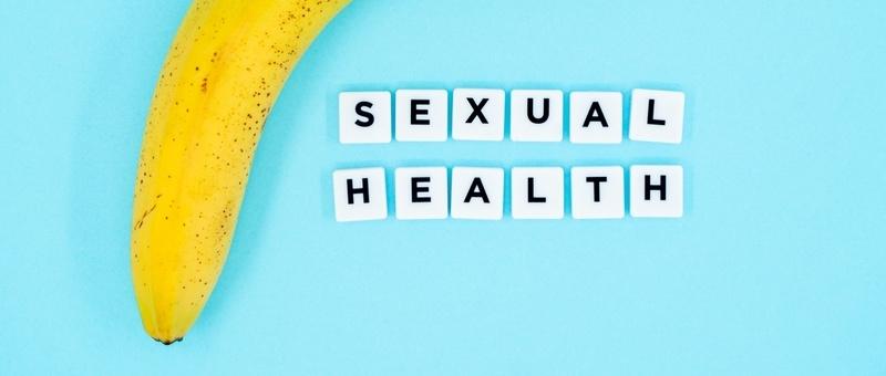 Tipo led - SALUD SEXUAL impreso en bloques blancos junto a plátano sobre fondo azul.
