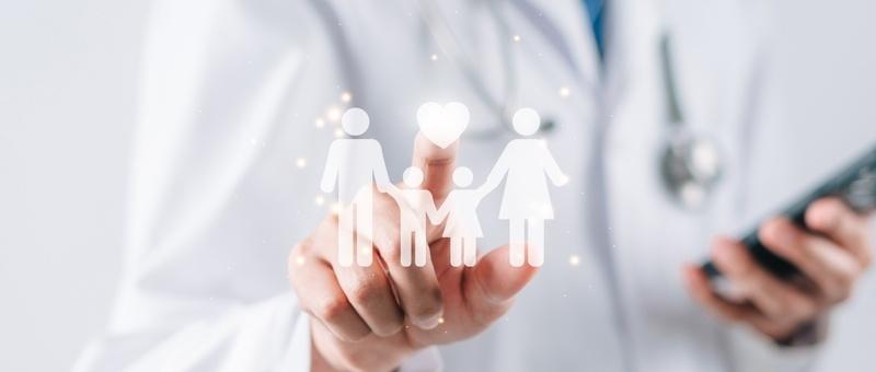 Profesional médico con bata blanca sosteniendo un icono familiar digital mientras utiliza un smartphone en la otra mano.