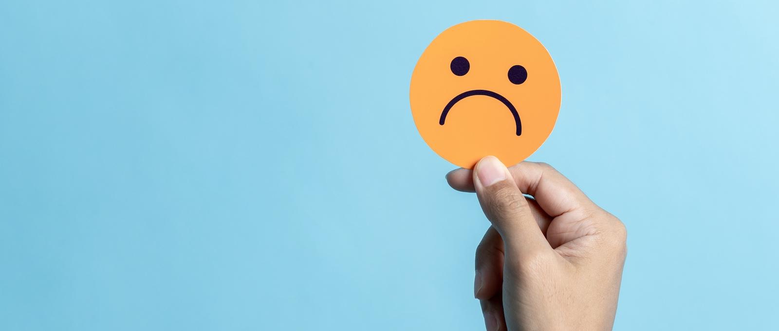 Un círculo naranja con una cara triste sobre fondo azul.