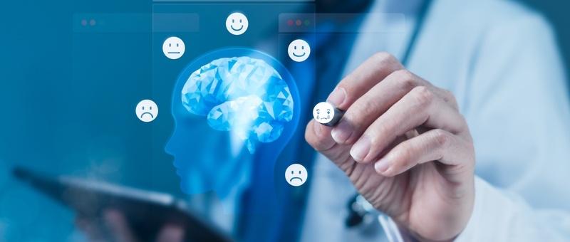 Iconos de emociones dibujados a mano alrededor de una silueta digital de cerebro, que representa la salud mental o la evaluación psicológica.