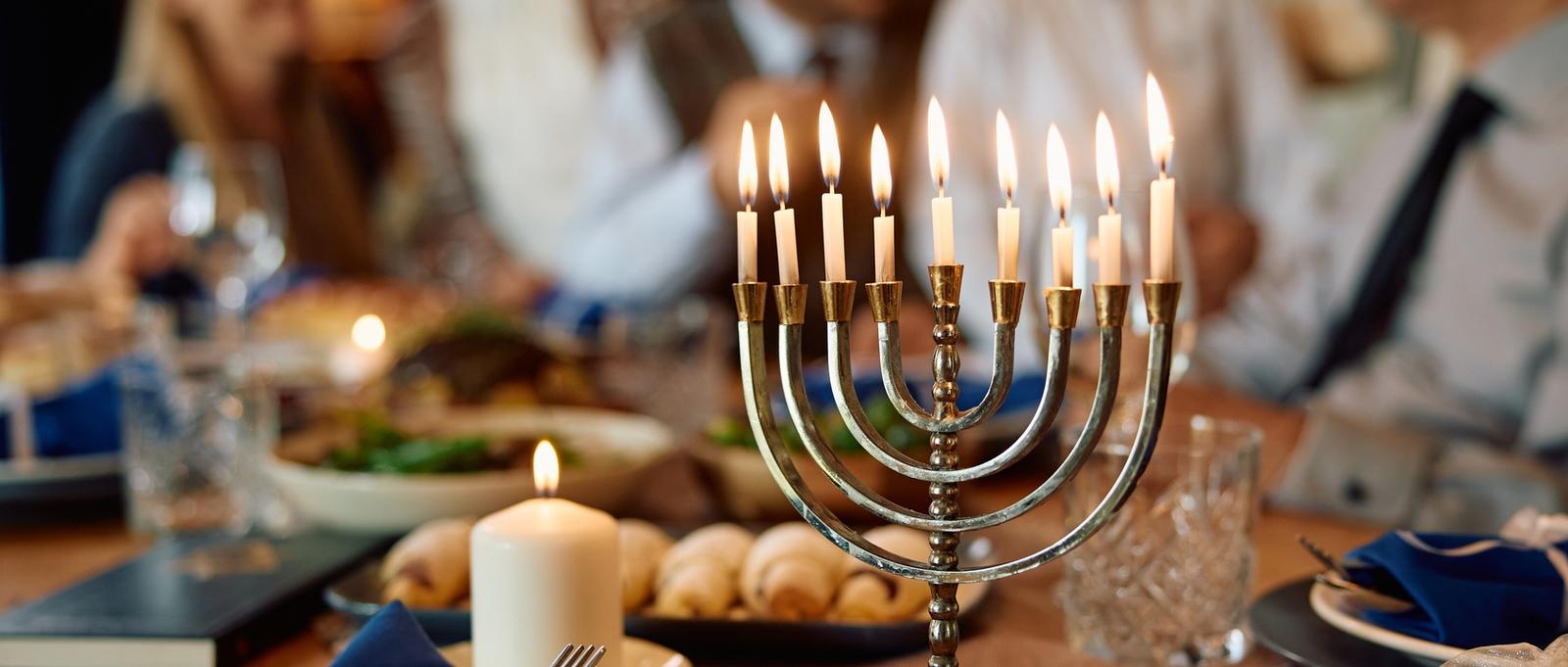 Menorah encendida con la familia judía al fondo en Hanukkah.