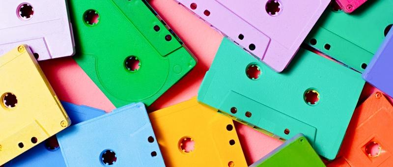 Music cassette tapes in bold assorted colours against a pink background.