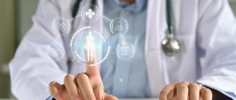 Médico con estetoscopio tocando interfaz sanitaria digital que muestra figura humana e iconos médicos.