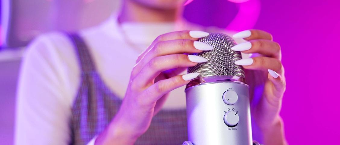 Uñas, ASMR y manos con micrófono, mujer y luces de neón con podcast, creación de contenidos y tecnología. Inicio, difusión y audio para aliviar el estrés con persona influencer con grabación para sonido.