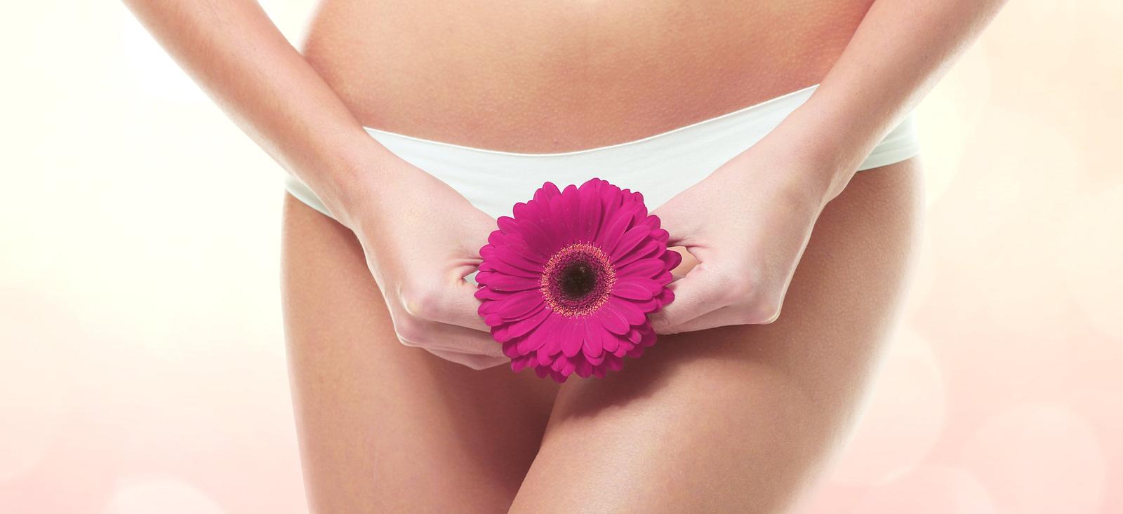 Primer plano de una mujer que sostiene una flor delante de su zona pública. Las imágenes conceptualizan una prueba de frotis.