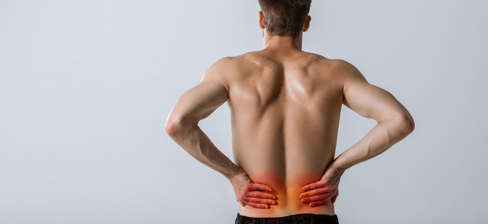 Un hombre sujetándose la parte baja de la espalda.