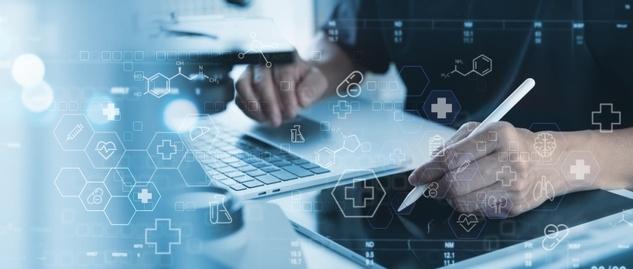 Persona trabajando en portátil y tableta digital con iconos médicos y gráficos sanitarios superpuestos en tonos azules.