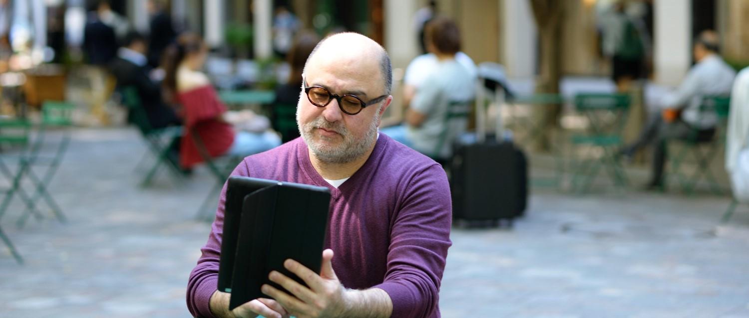 Hombre calvo sentado al aire libre leyendo una tableta