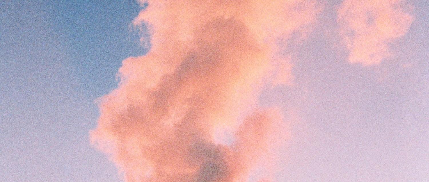 Una esponjosa formación de nubes rosas sobre un cielo azul al atardecer, creando una atmósfera de ensueño en tonos pastel.