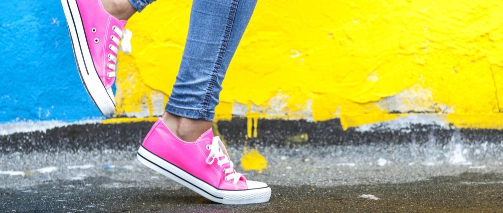 Mujer con zapatillas rosas contra pared amarilla y azul